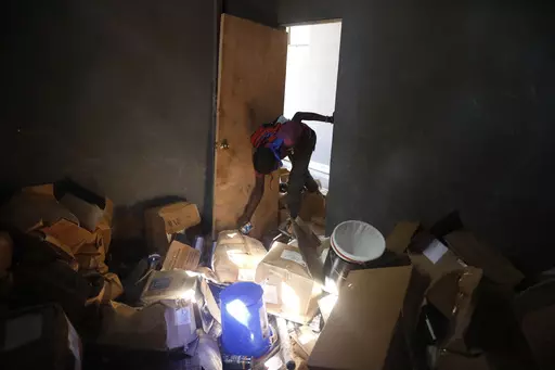 A hospital worker searches for recoverable items from a food depot at the Fontaine Hospital Center the day after it was broken into and robbed during an armed attack on the hospital in the Cité Soleil area of Port-au-Prince, Haiti, Thursday, Nov. 16, 2023. A heavily armed gang surrounded the hospital on Wednesday, trapping women, children and newborns inside until police rescued them, according to the director of the medical center. (AP Photo/Odelyn Joseph)