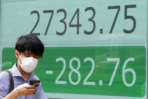 A person wearing a protective mask walks past an electronic stock board showing Japan's Nikkei 225 index at a securities firm Wednesday, Sept. 7, 2022, in Tokyo. Asian shares were mostly lower Wednesday, as pessimism prevailed about higher interest rates ahead and Wall Street shares fell for the fourth straight week. Oil prices fell, while the Japanese yen continued to decline against the U.S. dollar to nearly 144 yen. (AP Photo/Eugene Hoshiko)