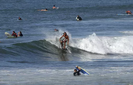 A surfer rides a wave in the Atlantic Ocean in Biarritz, southwestern France, Oct. 7, 2023. October was the fifth straight month that Earth set a record for the hottest month in recorded history. (AP Photo/Bob Edme, File)