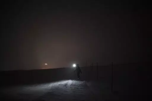 The Rev. Siv Limstrand walks with her rifle to the church's cabin in Bolterdalen, Norway, Monday, Jan. 9, 2023. For the lone pastor in this fragile, starkly beautiful environment, the challenge is to fulfill the church's historical mission of ministering to those in crisis while addressing a pressing and divisive contemporary challenge. "We pray every Sunday for everyone who's affected by climate change," Limstrand said. (AP Photo/Daniel Cole)