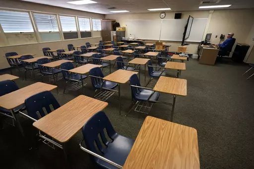 Math teacher Doug Walters sits among empty desks as he takes part in a video conference with other teachers to prepare for at-home learning at Twentynine Palms Junior High School in Twentynine Palms, Calif., Aug. 18, 2020. A new study finds that students around the world suffered historic setbacks in reading during the pandemic and even deeper losses in math, with test score decreases so wide that the United States climbed in global rankings simply by falling behind less sharply. (AP Photo/Grego