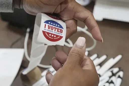 A precinct worker precuts "I Voted" stickers from a long roll prior to the site opening up for voters Tuesday, Nov. 5, 2024, in Jackson, Miss. (AP Rogelio V. Solis)