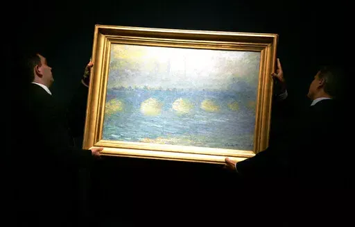 Two staff hang a Claude Monet 1904 painting 'Waterloo Bridge, temps couvert', for display at Christie's in London, Thursday, June 14, 2007. The painting was one of 60 pieces from the Paul G. Allen collection auctioned by Christie's in New York, on Wednesday, Nov. 9, 2022, bringing $1.5 billion in a single night. It sold for $64.5 million. (AP Photo/Sang Tan, File)