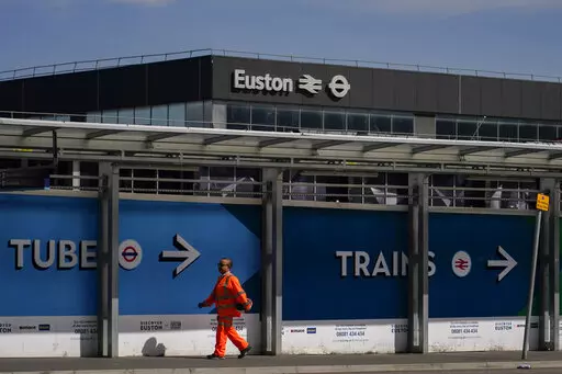 A construction worker walks past Euston station, in London, Tuesday, June 21, 2022. Tens of thousands of railway workers walked off the job in Britain on Tuesday, bringing the train network to a crawl in the country’s biggest transit strike for three decades. (AP Photo/Alberto Pezzali)