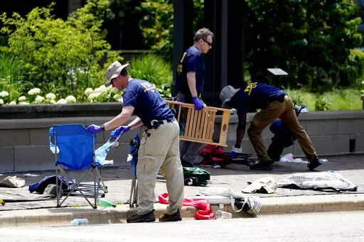 Members of the FBI's evidence response team remove personal belongings one day after a mass shooting in downtown Highland Park, Ill., Tuesday, July 5, 2022. A shooter fired on an Independence Day parade from a rooftop spraying the crowd with gunshots initially mistaken for fireworks before hundreds of panicked revelers of all ages fled in terror. (AP Photo/Charles Rex Arbogast)