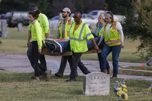 Researchers and burial oversight committee member Brenda Alford carry the first set of remains exhumed from the latest dig site in Oaklawn Cemetery to an onsite lab for further examination, Sept. 13, 2023, in Tulsa, Okla. A third set of remains with a gunshot wound has been found in the search for graves of victims of the 1921 Tulsa Race Massacre at a Tulsa cemetery, according to a state official. (Mike Simons/Tulsa World via AP, File)