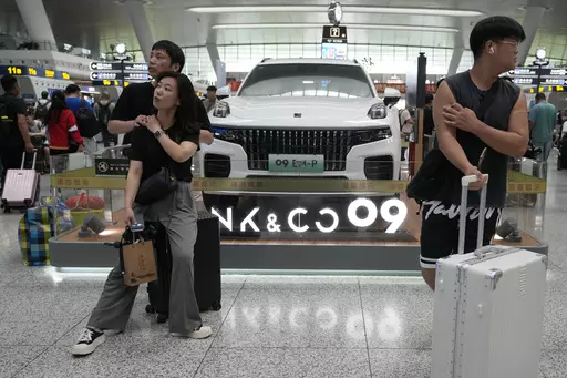 Passengers wait near a hybrid luxury SUV from China automaker Lynk&co displayed at the train station in Hangzhou in eastern China's Zhejiang province on Monday, July 3, 2023. Chinese automakers are winning over drivers as they make major inroads into Europe’s electric vehicle market, challenging long-established homegrown brands in an industry that’s key to the continent’s green energy transition. The European Union has launched an investigation into Beijing’s support for its EV industry