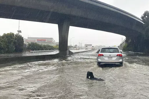 Traffic drives through flooded lanes on Highway 101 in South San Francisco, Calif., Saturday, Dec. 31, 2022. A flood watch is in effect across much of Northern California through New Year's Eve. Officials warned that rivers and streams could overflow and urged residents to get sandbags ready. (AP Photo/Jeff Chiu)