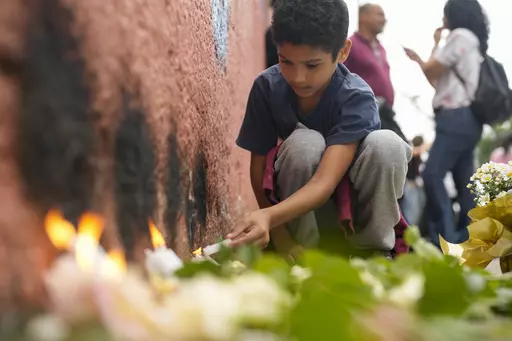 A student from the Thomazia Montoro public school lights a candle during a vigil asking for peace the day after a student stabbed a teacher to death at the school in Sao Paulo, Brazil, March 28, 2023. Brazil is grappling with a wave of violence in its schools. The government has sought input from independent researchers and convened a meeting on Tuesday, April 18, 2023, of ministers, mayors and Supreme Court justices to discuss possible solutions. (AP Photo/Andre Penner, File)