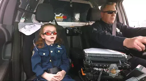 In this image from an April 2017 video provided by the Denver Police Department, Olivia Gant, who was 6 years old at the time, rides with Capt. Tim Scudder on a call in Denver. Olivia's mother, Kelly Turner, will be sentenced Wednesday, Feb. 9, 2022, after pleading guilty last month to child abuse resulting in death, charitable fraud and theft between $100,000 and $1 million, according to prosecutors. Authorities say she duped doctors about her daughter’s health, leading to unnecessary surgeri