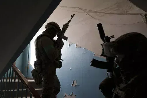 Security Service of Ukraine (SBU) servicemen enter a building during an operation to arrest suspected Russian collaborators in Kharkiv, Ukraine, Thursday, April 14, 2022. Ukrainian authorities are cracking down on anyone suspected of aiding Russian troops under laws enacted by Ukraine's parliament and signed by President Volodymyr Zelenskyy after the Feb. 24 invasion. Offenders face up to 15 years in prison for acts of collaborating with the invaders or showing public support for them. (AP Photo