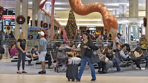 Holiday travelers pass by "Phoebe" the Flamingo at the Tampa International Airport, Friday, Dec. 22, 2023, in Tampa, Fla. Conditions were mostly nice for travelers flying ahead of and on Christmas Day this year, but some naughty disruptions plagued those flying with Southwest Airlines again this year. By midday Monday, Dec. 25, only 138 flights within, into or out of the U.S. had been canceled and 1,366 were delayed, according to FlightAware, a tracking website. (AP Photo/Chris O'Meara, File)
