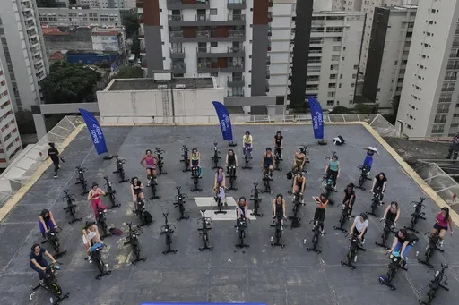 Women attend a spinning class on a hotel building's helipad in Sao Paulo, Tuesday, March 18, 2025. (AP Photo/Andre Penner)