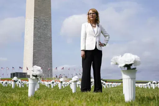 Former congresswoman and gun violence survivor Gabby Giffords stands among vases of flowers that make up the Gun Violence Memorial installation near the Washington Monument on the National Mall in Washington, Tuesday, June 7, 2022. The flowers are meant to represent the number of Americans who die from gun violence each year. (AP Photo/Patrick Semansky)