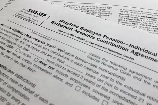 In this April 2, 2018, file photo, an IRS Form 5305, Simplified Employee Pension — Individual Retirement Accounts Contribution Agreement is shown in New York. Companies have long helped their workers save for retirement through 401(k)s and other workplace plans. But recent SECURE 2.0 legislation has blessed a newer trend: employers creating emergency savings options that could encourage workers to save more and avoid raiding their retirement funds. (AP Photo/Jenny Kane, File)