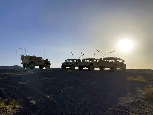 Army vehicles on the ridge, as soldiers from the 2nd Brigade, 1st Cavalry Division, prepare to attack the enemy in the town nearby, during an early morning training exercise at the National Training Center at Fort Irwin, Calif., April 12, 2022. (AP Photo/Lolita C. Baldor)