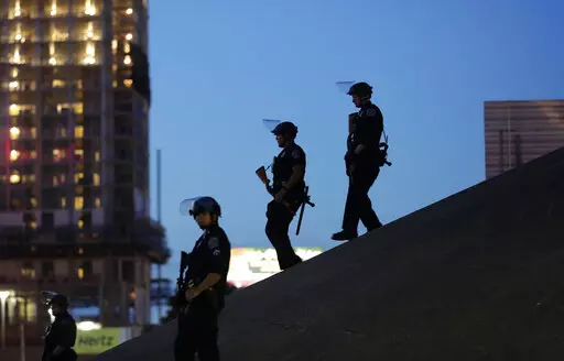 Austin police keep watch as demonstrators gather on June 4, 2020, in downtown Austin, Texas, as they protest the death of George Floyd, a black man who died after being restrained by Minneapolis police officers on Memorial Day. The Austin City Council on Thursday, Feb. 17, 2022, approved paying a combined $10 million to two people injured when officers fired beanbag rounds into crowds during the 2020 social justice protests, including a college student who suffered brain damage.   (AP Photo/Eric