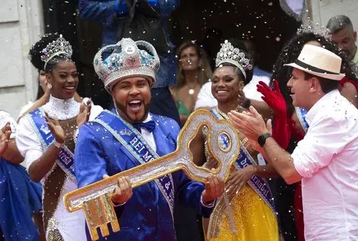 Carnival King Momo, Wilson Dias da Costa Neto, holds the key of the city as the Rio de Janeiro Mayor Eduardo Paes, right, applauds during a ceremony marking the official start of Carnival in Rio de Janeiro, Brazil, Wednesday, April 20, 2022. (AP Photo/Bruna Prado)