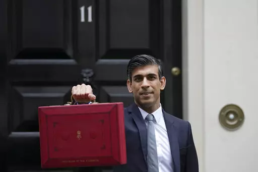 Britain's Chancellor of the Exchequer Rishi Sunak holds up the traditional ministerial red dispatch box as he leaves for the House of Commons to deliver the Budget in London, Oct. 27, 2021. Revelations that Prime Minister Boris Johnson and his staff partied while Britain was in a coronavirus lockdown have provoked public outrage and led some members of his Conservative Party to consider ousting their leader. If they manage to push Johnson out — or if he resigns — the party would hold a leade