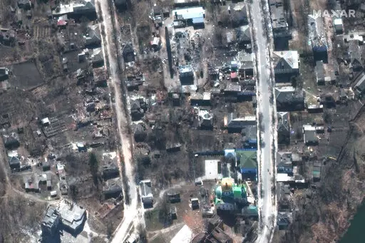 This satellite image provided by Maxar Technologies shows damaged buildings during fighting in Izium, Ukraine, on March 24, 2022. On Friday, Sept. 30, The Associated Press reported on stories circulating online incorrectly claiming that Russian forces did not kill a Ukrainian family whose graves were pictured in a wooded area among scores of others. (Maxar Technologies via AP)