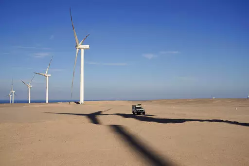 A vehicle drives near wind turbines at Lekela wind power station, near the Red Sea city of Ras Ghareb, some 300 km (186 miles), from Cairo, Egypt, Oct. 12, 2022. The U.N. climate summit is back in Africa after six years and four consecutive Europe-based conferences. The conference — known as COP27 — will be held in the resort city of Sharm el-Sheikh in Egypt. (AP Photo/Amr Nabil, File)