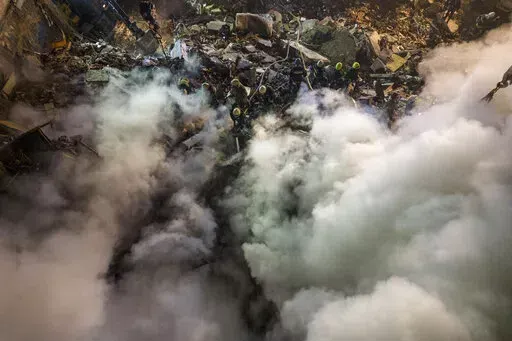 Emergency workers clear the rubble after a Russian rocket hit a multistory building leaving many people under debris in the southeastern city of Dnipro, Ukraine, Saturday, Jan. 14, 2023. (AP Photo/Evgeniy Maloletka)