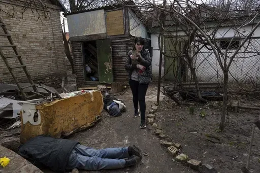 Ira Gavriluk holds her cat as she walks past the corpses of her husband and her brother, who were killed in Bucha, on the outskirts of Kyiv, Ukraine, April 4, 2022. The scenes that emerged from this town near Kyiv a year ago after it was retaken from Russian forces have indelibly linked its name to the savagery of war. (AP Photo/Rodrigo Abd, File)