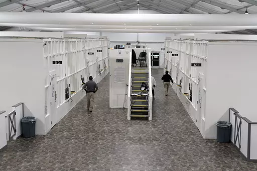 Agents walk among rooms at a Border Patrol holding facility on Dec. 15, 2023, in Tucson, Ariz. U.S. asylum officers were instructed nearly a year ago to apply a higher screening standard on people who cross the border illegally to claim asylum after passing through another country. But they are too understaffed to have much impact. (AP Photo/Gregory Bull, File)