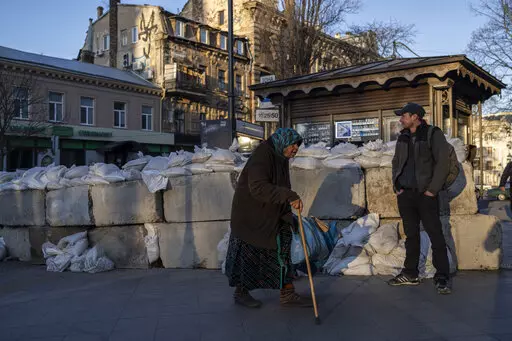 An elderly woman walks pass concrete blocks topped with sandbags at a street in Odesa, southern Ukraine, on Tuesday, March 22, 2022.(AP Photo/Petros Giannakouris)