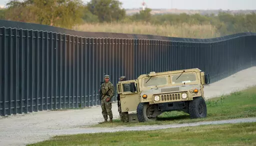 National Guardsmen stands watch over a fence near the International bridge where thousands of Haitian migrants have created a makeshift camp, on Sept. 18, 2021, in Del Rio, Texas. Former Trump administration officials are pressing Republican border governors to declare an "invasion" along the U.S.-Mexico border. It comes as Texas Gov. Greg Abbott says he'll announce "unprecedented actions" on Wednesday to deter migrants coming to Texas. (AP Photo/Eric Gay, File)