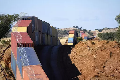 A long row of double-stacked shipping containers provide a new wall between the United States and Mexico in the remote section area of San Rafael Valley, Ariz., Thursday, Dec. 8, 2022. Arizona Gov. Doug Ducey will take down a makeshift wall made of shipping containers at the Mexico border, settling a lawsuit and political tussle with the U.S. government over trespassing on federal lands. (AP Photo/Ross D. Franklin, File)