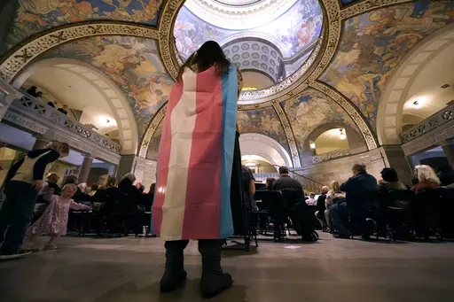 Glenda Starke wears a transgender flag as a counter protest during a rally in favor of a ban on gender-affirming health care legislation, March 20, 2023, at the Missouri Statehouse in Jefferson City, Mo. (AP Photo/Charlie Riedel, File)