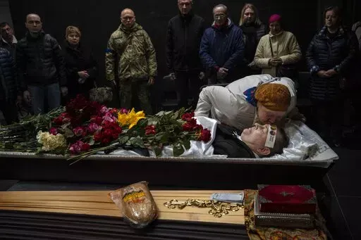 Natalya kisses her brother Sergiy Muravyts'kyi, 61, who was killed by Russian soldiers in the village of Mriya, which means Dream, in Ukrainian, during a ceremony before his cremation in Baikove cemetery, Kyiv, Ukraine, Thursday, March 24, 2022. (AP Photo/Rodrigo Abd)