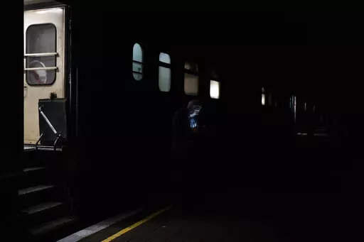 A man checks his phone before boarding the Kherson-Kyiv train at the Kherson railway station, southern Ukraine, Saturday, Nov. 26, 2022. Fleeing shelling, hundreds of civilians on Saturday streamed out of the southern Ukrainian city whose recapture they had celebrated just weeks earlier. (AP Photo/Bernat Armangue)