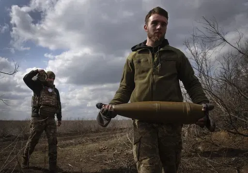 Ukrainian soldiers carry shells to fire at Russian positions on the front line, near the city of Bakhmut, in Ukraine's Donetsk region, on March 25, 2024. Approval by the U.S. House of a $61 billion package for Ukraine puts the country a step closer to getting an infusion of new firepower. But the clock is ticking. Russia is using all its might to achieve its most significant gains since the invasion by a May 9 deadline. (AP Photo/Efrem Lukatsky, File)
