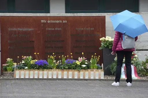 A woman looks at candles at the schoolyard of the Joseph-Koenig high school in Haltern, Germany, ten years after 16 pupils and two teachers of the school died in the Germanwings crash in the French Alps, Monday, March 24, 2025. (AP Photo/Martin Meissner)