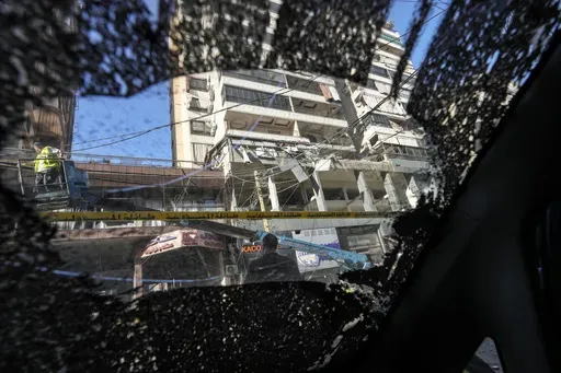 The damaged building at the site of an Israeli airstrike, seen from the shattered window of a car, in Beirut's southern suburb, Thursday, Sept. 26, 2024. (AP Photo/Hassan Ammar)