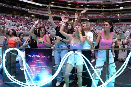 Concertgoers dance during Coldplay's Music of the Spheres world tour on Thursday, May 12, 2022, at State Farm Stadium in Glendale, Ariz. The band has included energy-storing stationary bikes to their latest world tour, encouraging fans to help power the show as part of a push to make the tour more environmentally friendly. (Photo by Rick Scuteri/Invision/AP)