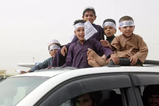 Children hold Taliban flags during a celebration marking the second anniversary of the withdrawal of U.S.-led troops from Afghanistan, in Kandahar, south of Kabul, Afghanistan, Tuesday, Aug. 15, 2023. (AP Photo/Abdul Khaliq)