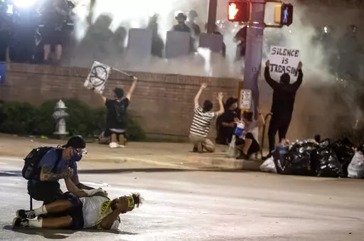 In this May 30, 2020 file photo, people help a protester after he was shot with a rubber bullet under Interstate 35 freeway in Austin Texas while protesting the death of George Floyd. The Austin City Council on Thursday, Feb. 17, 2022 approved paying a combined $10 million to two people injured when officers fired beanbag rounds into crowds during the 2020 social justice protests, including a college student who suffered brain damage. (Ricardo B. Brazziell/Austin American-Statesman via AP, File)
