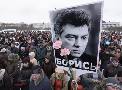 In this Sunday, Feb. 26, 2017 file photo, People gather in memory of opposition leader Boris Nemtsov, portrait in center, in St. Petersburg, Russia. Once deputy prime minister under Boris Yeltsin, Nemtsov was a popular politician and harsh critic of Putin. On a cold February night in 2015, he was gunned down by assailants on a bridge adjacent to the Kremlin as he walked with his girlfriend in a death that sent shockwaves across the country. (AP Photo/Dmitri Lovetsky, file)