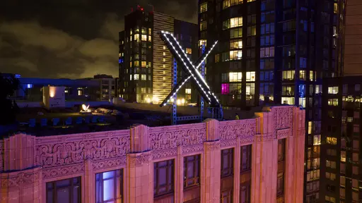 Workers install lighting on an "X" sign atop the company headquarters, formerly known as Twitter, in San Francisco, on July 28, 2023. The social media platform X says it is trying to take action on a flood of posts sharing graphic media, violent speech and hateful conduct about the latest war between Israel and Hamas. (AP Photo/Noah Berger, File)