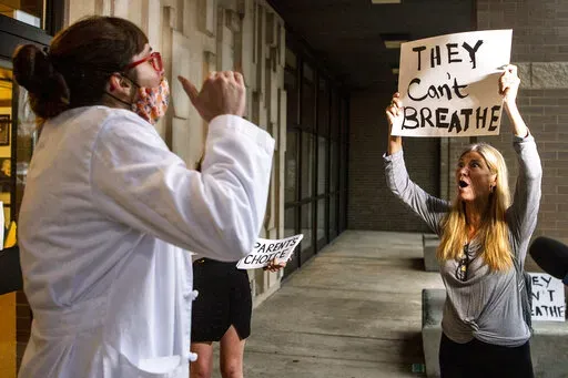 Dr. Brooke Decker, left, of Marshall, Director of Infection Prevention, argues with Dana Gibson about her opposition to a mask mandate for students before the North Allegheny School District school board regarding the district's mask policy, Aug. 25, 2021, at at North Allegheny Senior High School in McCandless, Pa. During earlier surges of the COVID-19 pandemic, some governors ordered business closures, issued mask mandates and required vaccines in certain settings. Some even required quarantine