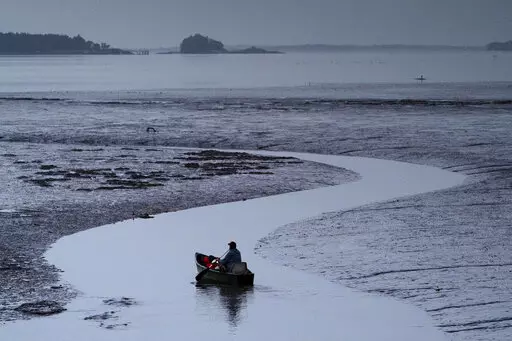 Clam digger Scott Lavers paddles his canoe on his way to work on a mudflat exposed by the receding tide, in this Friday, Sept. 4, 2020, file photo in Freeport, Maine. Warming waters and invasive species are threatening a way of life for many in the country's seafood industry. (AP Photo/Robert F. Bukaty)