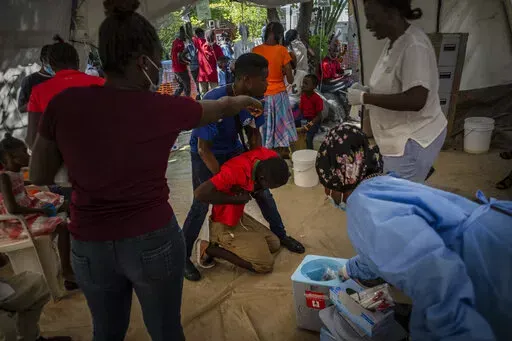 A youth suffering from cholera symptoms is helped upon arrival at a clinic run by Doctors Without Borders in Port-au-Prince, Haiti, Thursday, Oct. 27, 2022. For the first time in three years, people in Haiti have been dying of cholera, raising concerns about a potentially fast-spreading scenario and reviving memories of an epidemic that killed nearly 10,000 people a decade ago. (AP Photo/Ramon Espinosa)