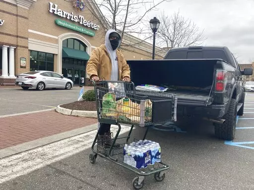 Chris Stokes picks up extra provisions at a grocery store in Norfolk, Va., on Friday Jan. 21, 2022, as the city prepares for an upcoming snowstorm.   (AP Photo/Ben Finley)
