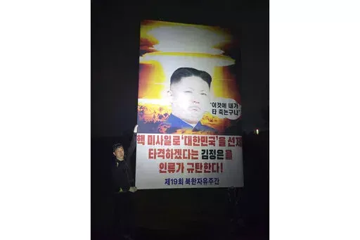 Park Sang-hak, a North Korean defector-turned-activist, holds a placard condemning North Korean leader Kim Jong Un in the border town of Paju, South Korea, Saturday, Oct. 1, 2022. South Korean activists say they clashed with police while launching balloons carrying anti-Pyongyang propaganda materials across the North Korean border, ignoring their government's plea to stop such activities the North has threatened to respond with "deadly" retaliation. The signs read "Entire humanity denounces Kim 
