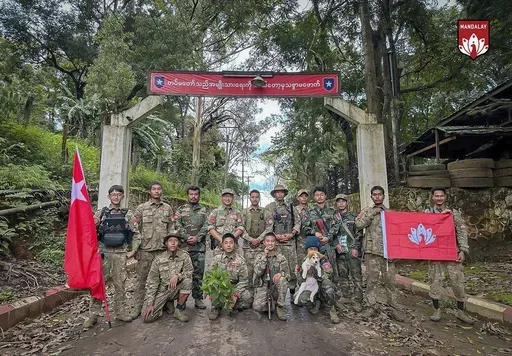 In this photo provided by Mandalay People's Defence Force, its members pose for a photograph in front of the gate of the captured army battalion in Mogok township in Mandalay region, Myanmar, on July 25, 2024. (Mandalay People's Defence Force via AP)