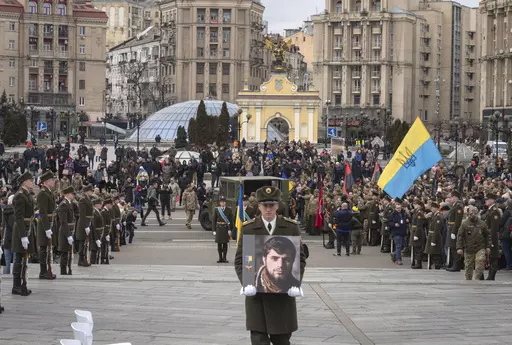 A serviceman carry a photo of Ukrainian officer Dmytro Kotsiubaylo, code-named "Da Vinci", during a commemoration ceremony in Independence Square in Kyiv, Ukraine, Friday, March 10, 2023. Kotsiubaylo was killed three days ago in a battle near Bakhmut in the Donetsk region. (AP Photo/Efrem Lukatsky)