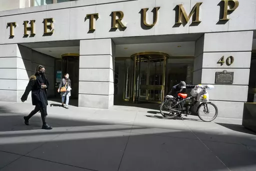 Pedestrians and a food delivery man are seen outside the Trump building on Wall Street, in New York's Financial District, March 23, 2021. (AP Photo/Mary Altaffer, File )
